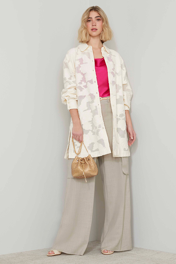 Modella indossa camicia con ricamo di colore panna e top di colore fucsia